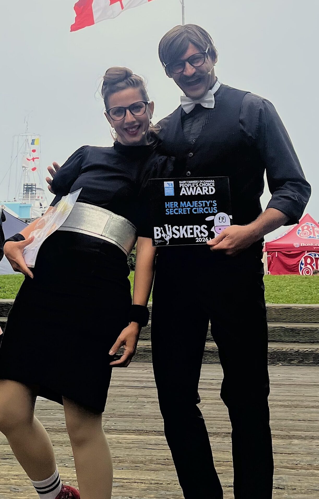 Agents Butterfly and Honeymoon posing with award. Canadian flag in background.